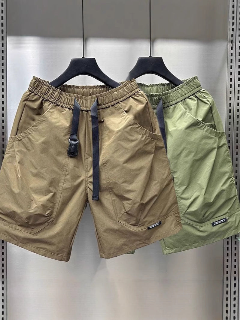 5. Pair of cargo shorts: one khaki and one light green, hanging side by side on black hangers.