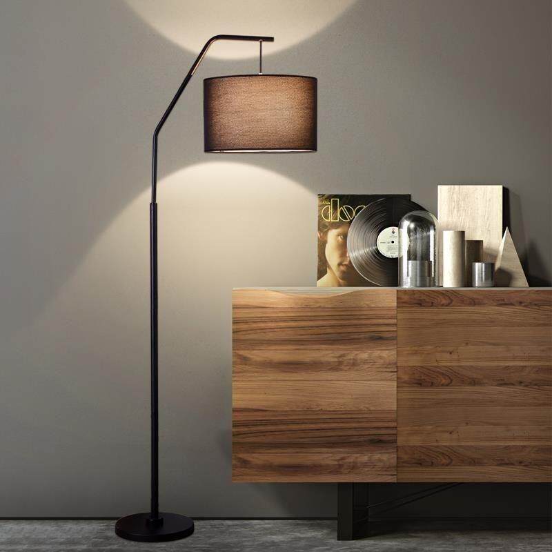 Modern Nordic arc floor lamp with brown fabric shade in contemporary living room setting next to wooden console table