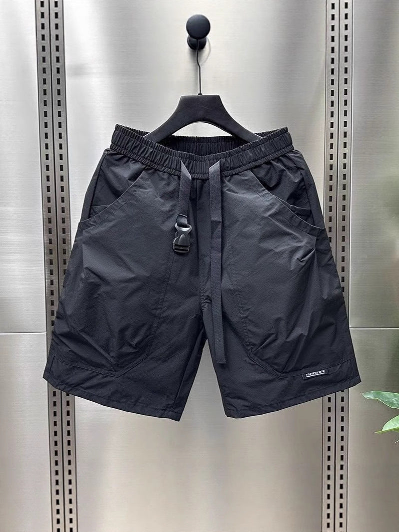 Black cargo shorts with multiple pockets and black drawstring waist, shown on a hanger.