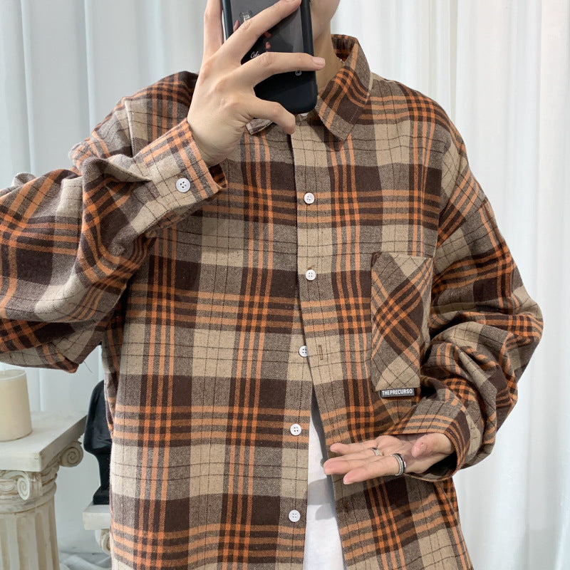 Man in a khaki and orange oversized plaid flannel shirt taking a mirror photo