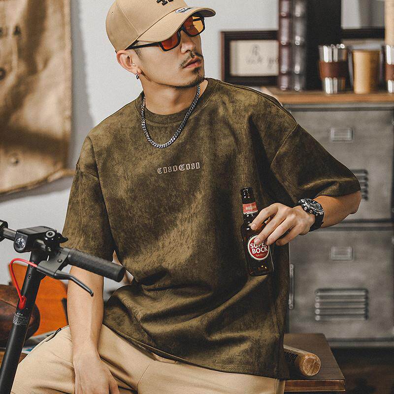 Men’s olive suede T-shirt front view, soft velvety fabric with subtle ECHHERE chest print, relaxed oversized crewneck on young model with chain necklace and cap