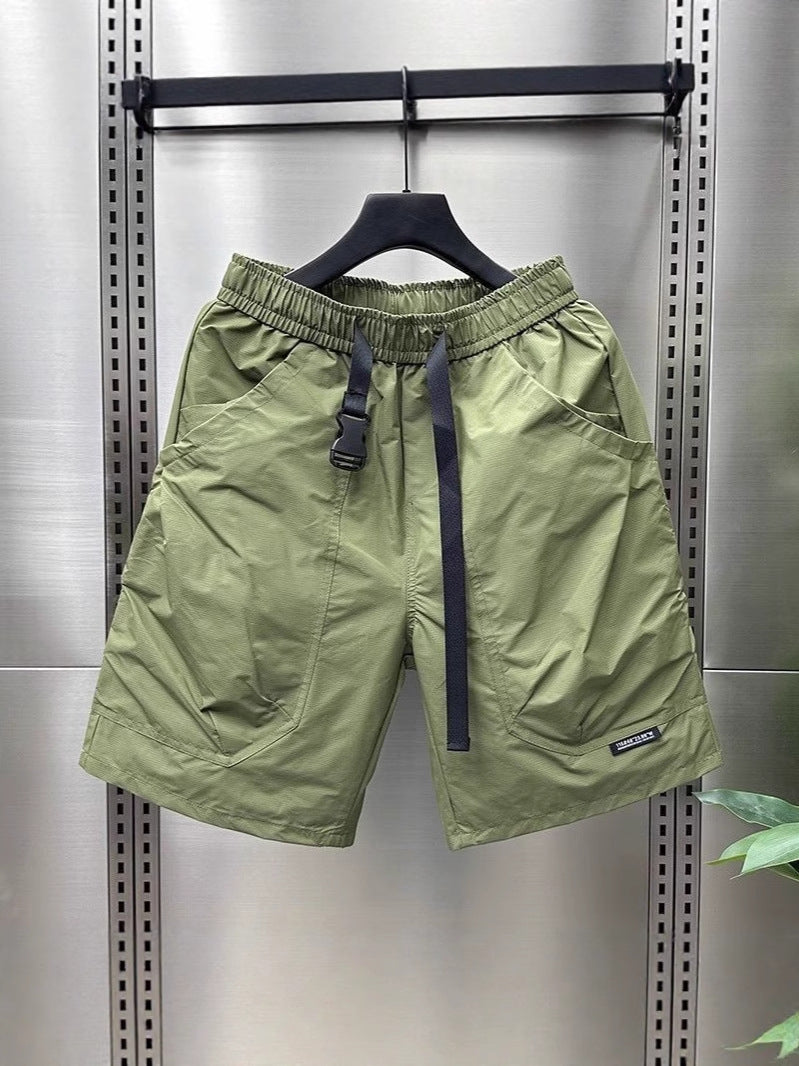 Light olive green cargo shorts with drawstring waist and side pockets, displayed on a hanger.