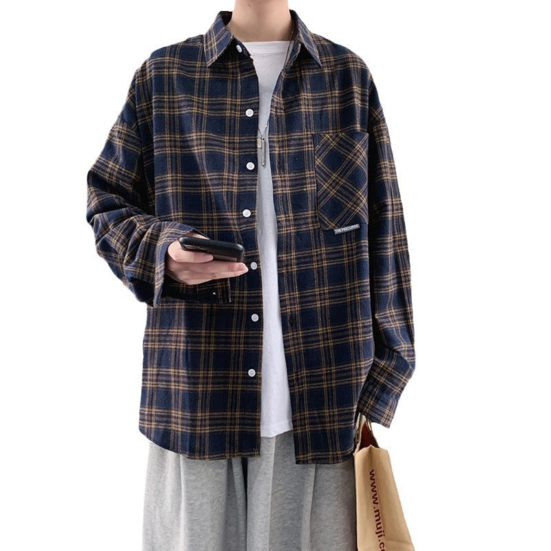 Men's navy blue loose fit plaid flannel shirt worn open over a white tee with gray pants