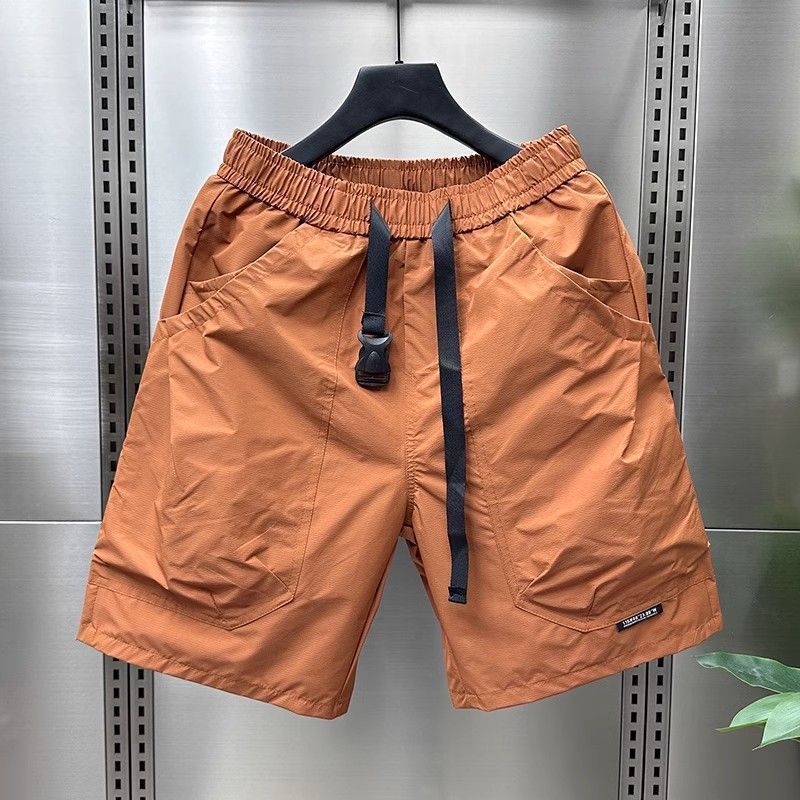 Orange cargo shorts with multiple utility pockets and black drawstring