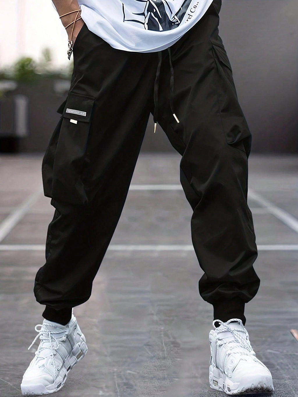 Person wearing black men’s slim fit cargo pants and white sneakers on a court
