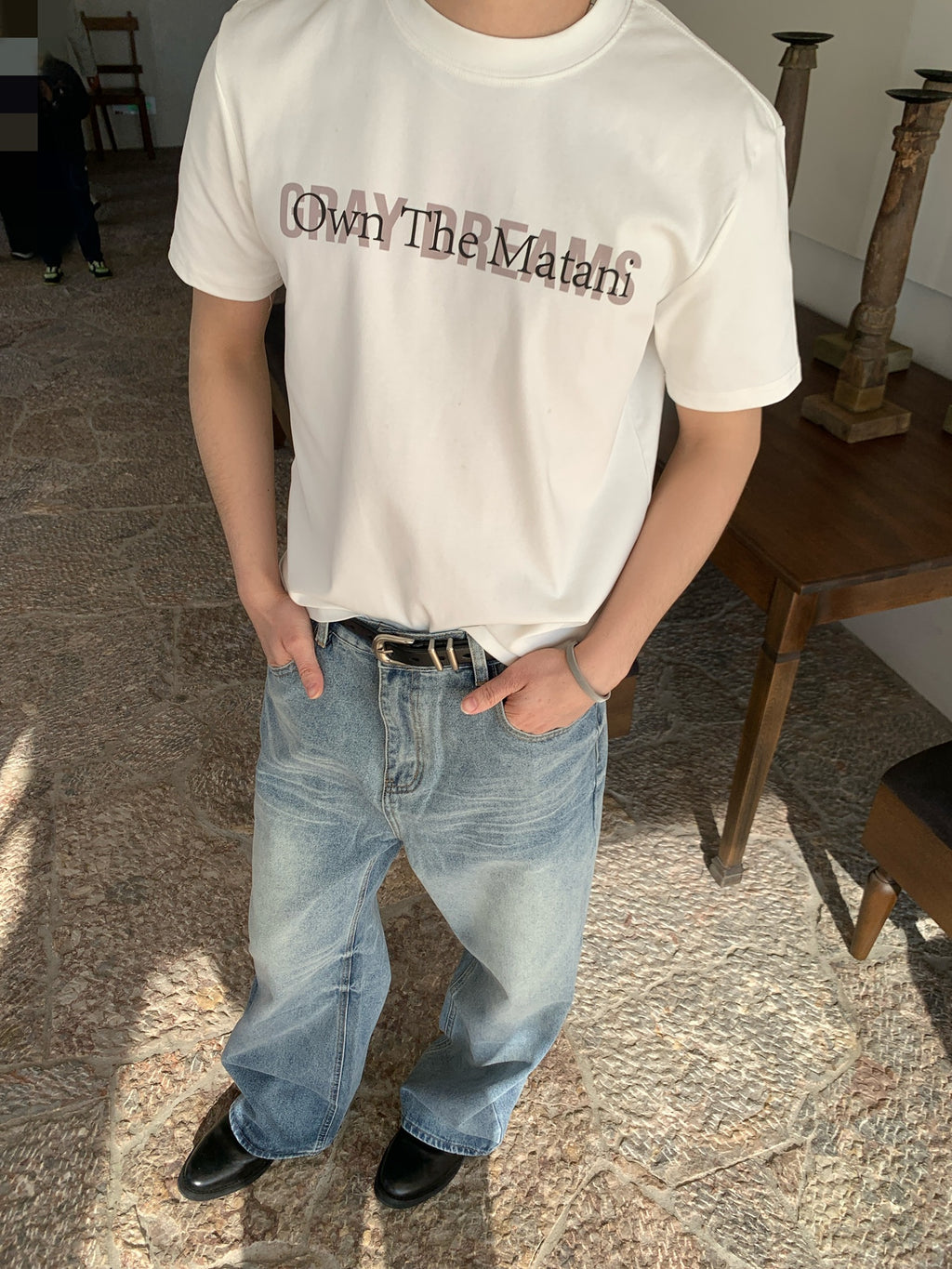 Front view of relaxed straight leg baggy jeans in light blue wash, mid waist fit, hands in pockets with white tee.