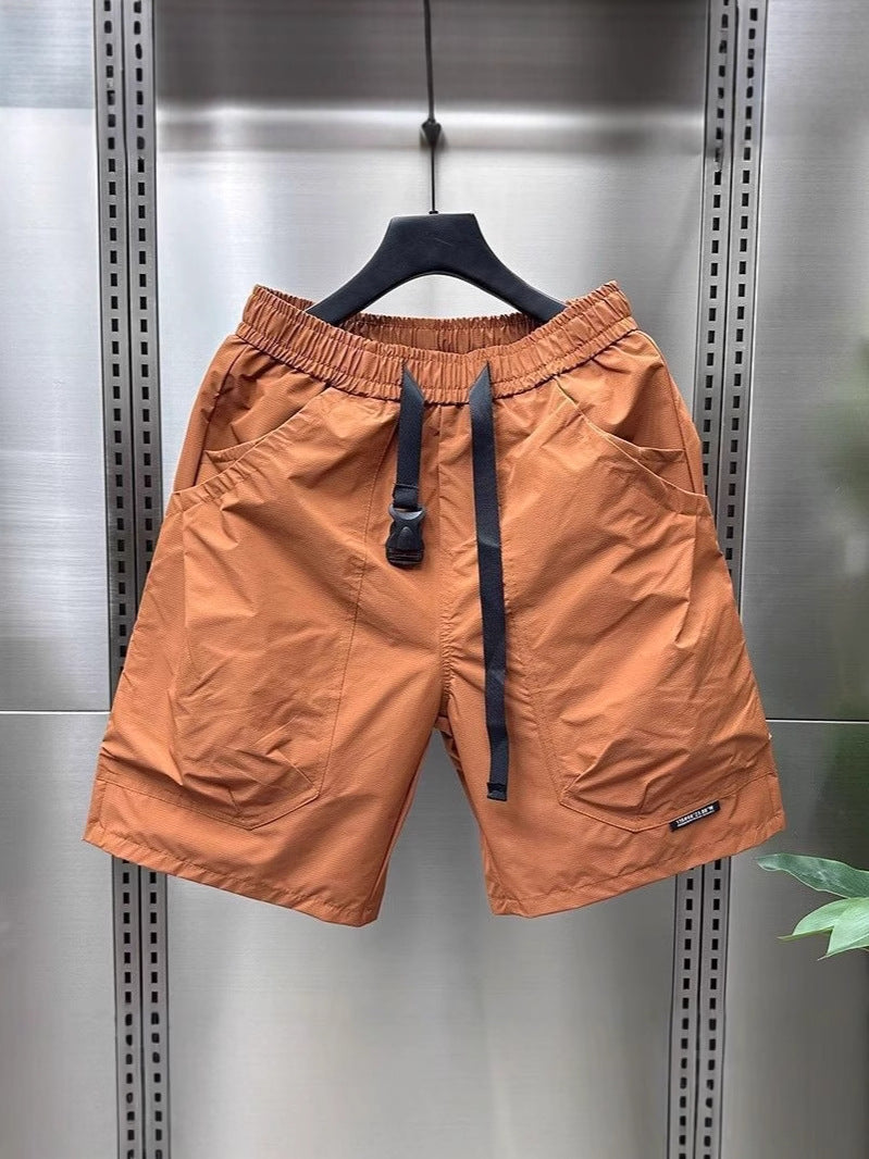 Bright orange cargo shorts with black drawstring and cargo pockets, hanging on a black hanger.