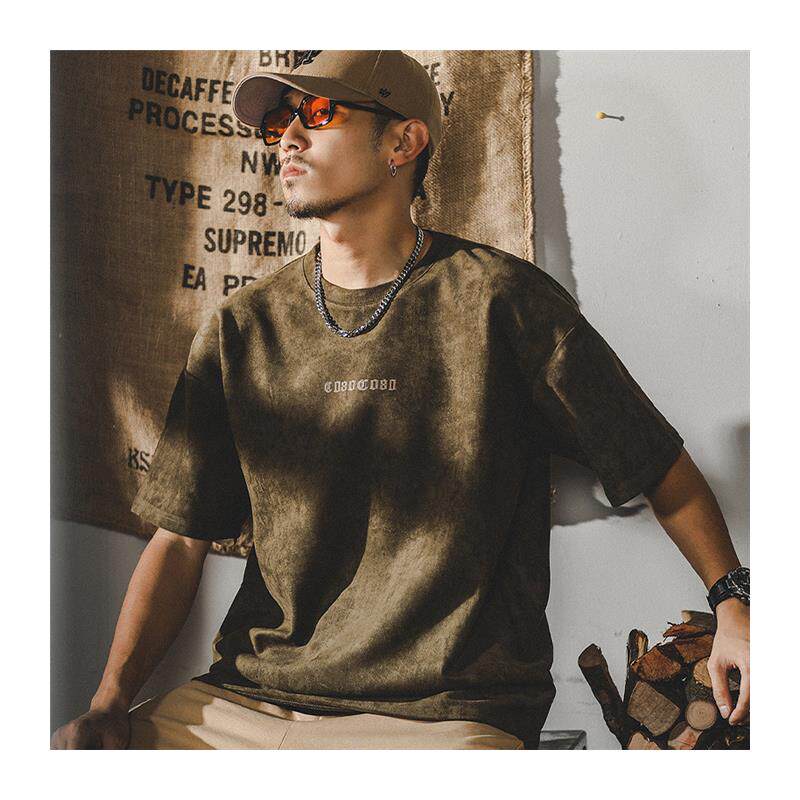 Suede T-shirt in rich olive tone, front view on young man with necklaces and sunglasses, buttery soft hand-feel, relaxed fit streetwear style
