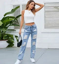 Women’s ripped straight-leg jeans in light blue worn with white crop top and black mini bag, casual streetwear outfit