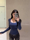 Woman taking mirror selfie in slim fit navy blue long sleeve cotton spandex U-neck top, arms at sides