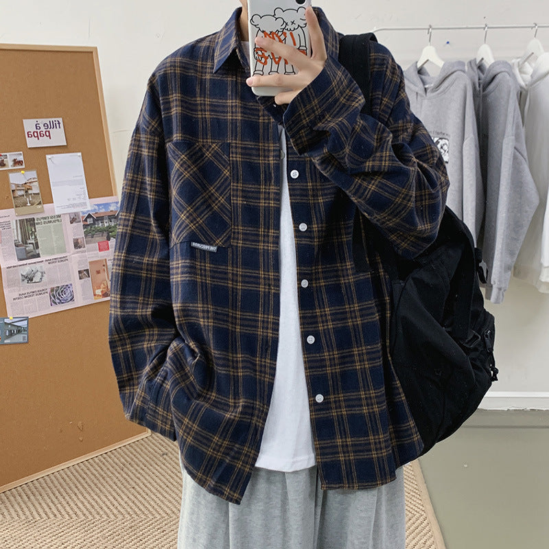 Man wearing a navy blue oversized flannel plaid shacket over a white tee, front view